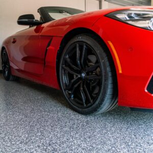 A luxury car parked in a garage with an epoxy floor coating, showcasing the floor's smooth, durable, and glossy finish, complementing the high-end vehicle. Elite Coatings offers fast-installation of polyurea concrete coatings for Houston home and businesses.